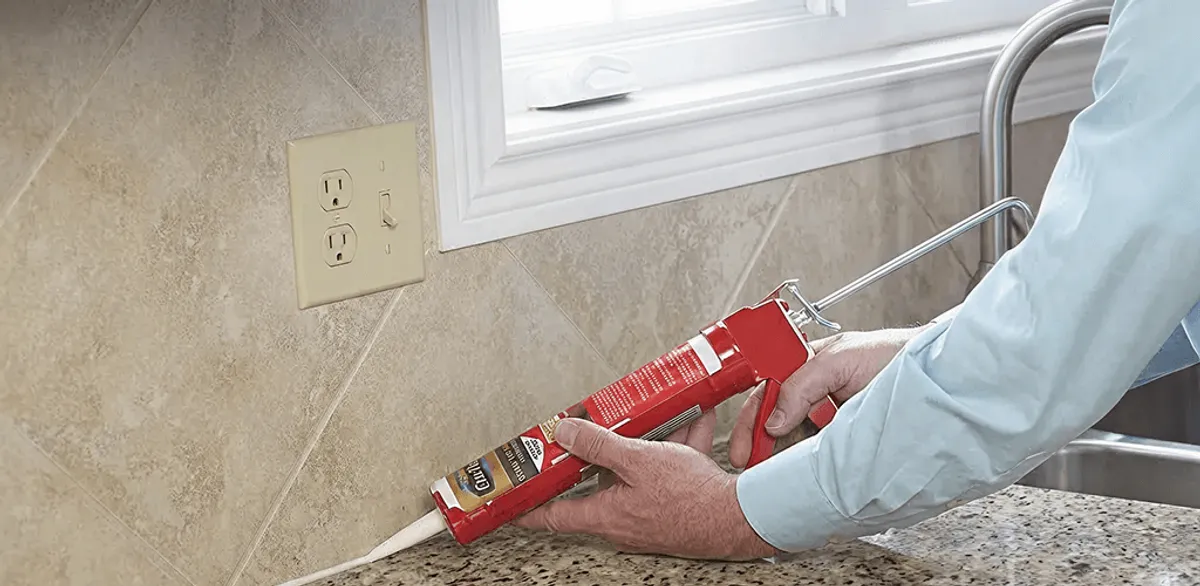 Handyman applying caulk along a kitchen backsplash and countertop seam in Riverside, CA