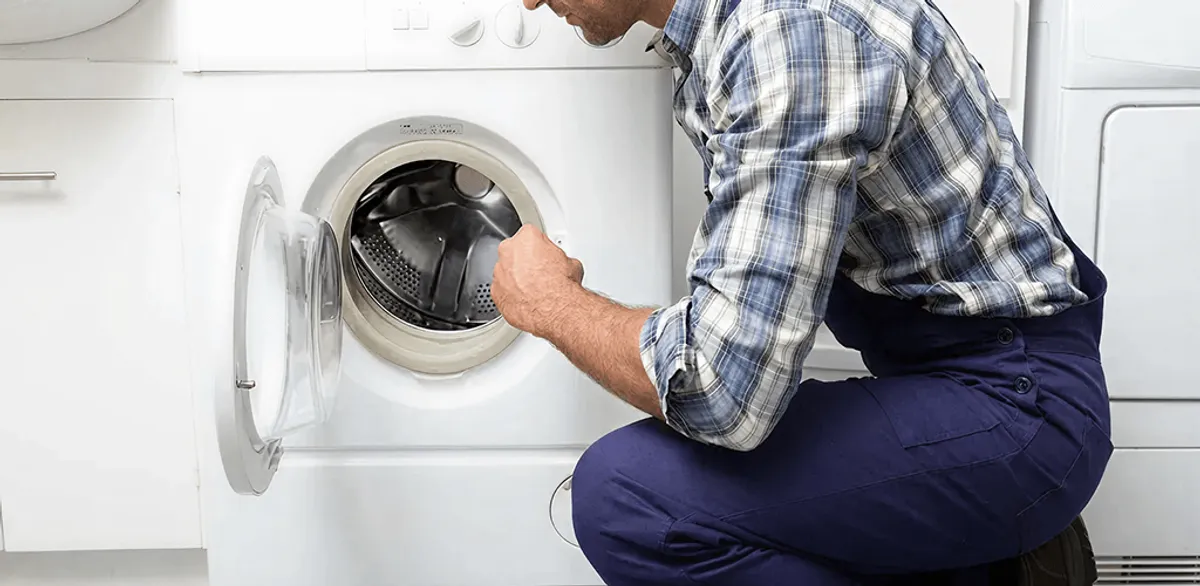 Handyman inspecting a dryer drum and internal parts for repair in Riverside, CA