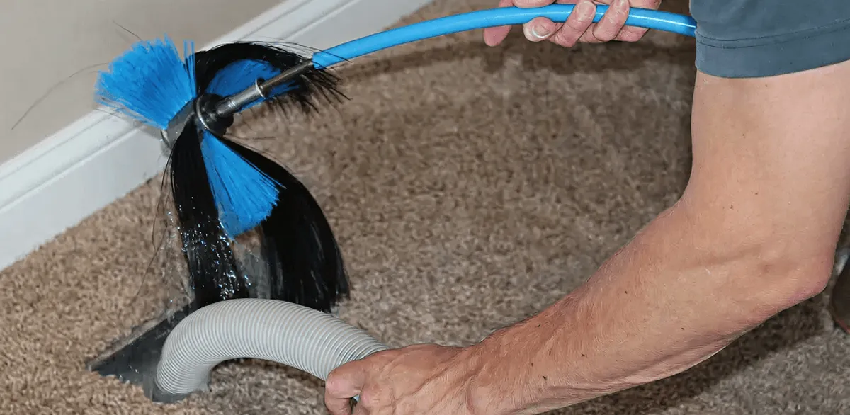 Dryer vent cleaning technician brushing lint from a vent line in Riverside, CA