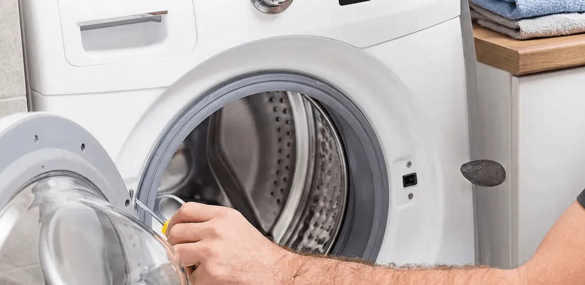 Handyman repairing a front-load washing machine and inspecting the drum in Riverside, CA